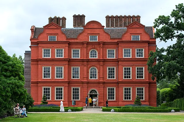 The red-brick Dutch-gabled facade of Kew Palace with its clipped box hedges and lawn