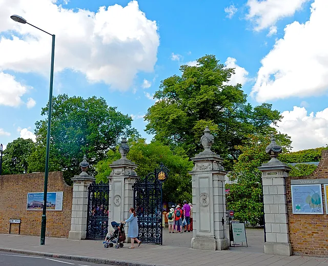 I pilastri di pietra e i cancelli di ferro battuto nero di Victoria Gate, l'ingresso principale, sotto il cielo azzurro