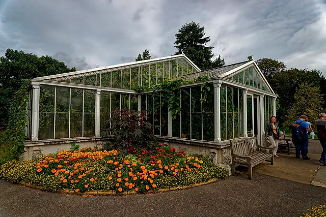 The glass Waterlily House with a bed of orange marigolds at its foot and a cloudy sky